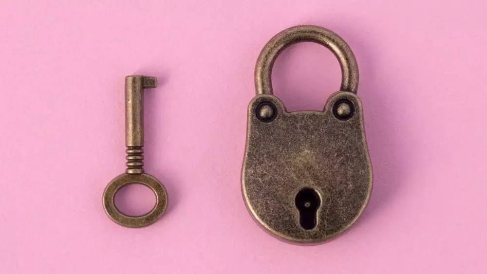 chastity lock and key on pink background