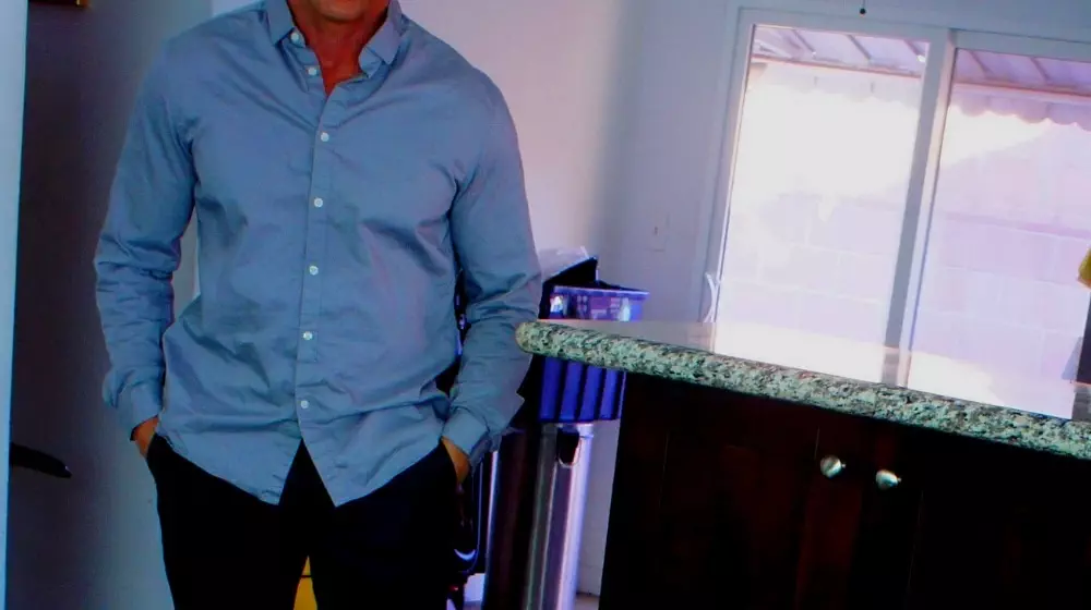 guy standing in kitchen wearing a smart shirt and jeans