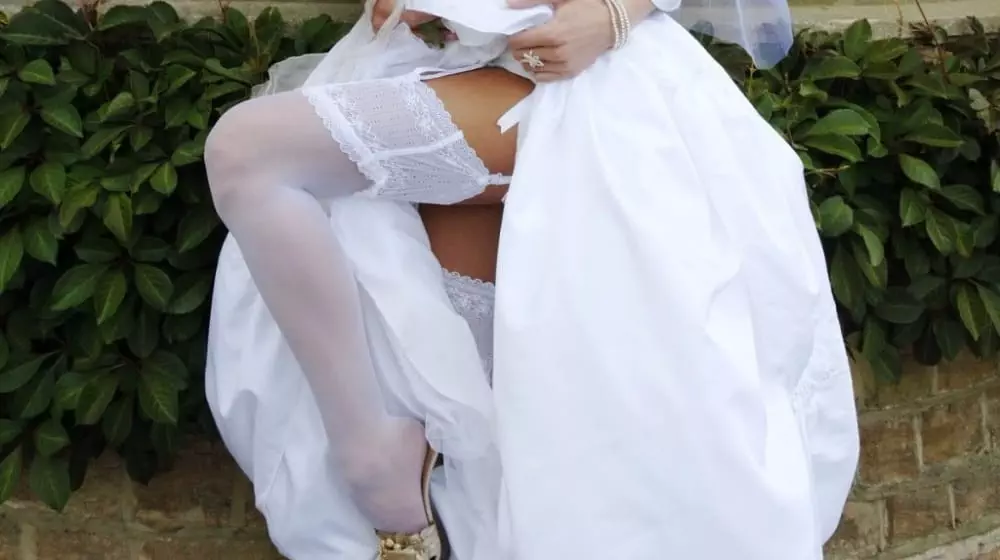 lady in wedding dress pulling up her dress to show her stockings
